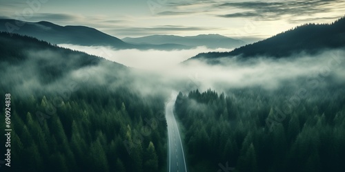 Aerial top view mountain road in dark green foggy forest photo