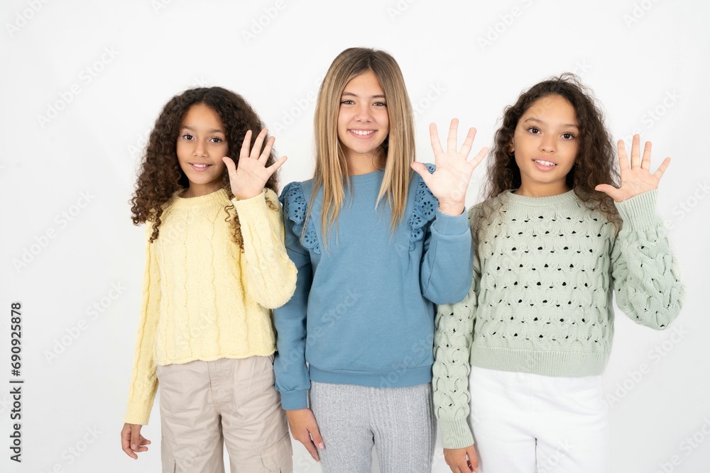 Three beautiful multiracial kid girls showing and pointing up with fingers number five while smiling confident and happy. Three beautiful multiracial kid girls showing and pointing up with fingers number five while smiling confident and happy.