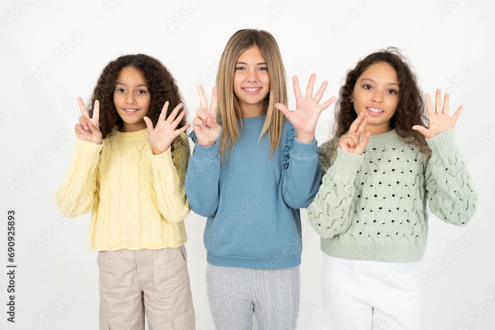 Three beautiful multiracial kid girls showing and pointing up with fingers number seven while smiling confident and happy. Three beautiful multiracial kid girls showing and pointing up with fingers number seven while smiling confident and happy.