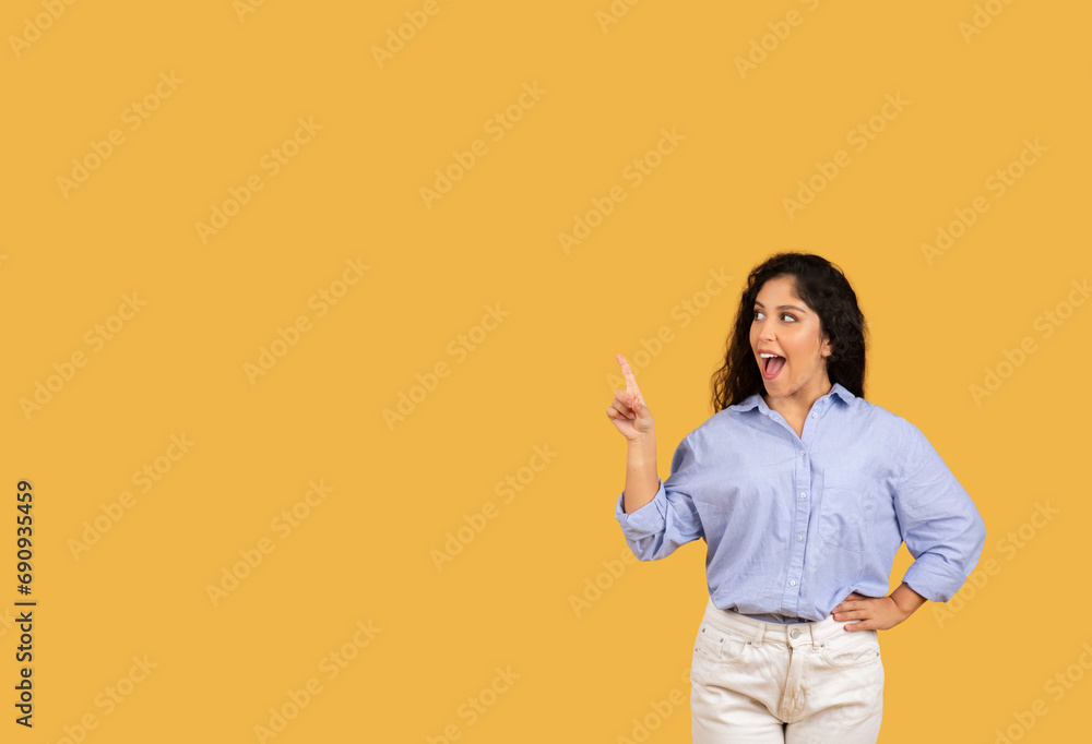 Cheerful latin millennial brunette woman in casual with open mouth point finger at empty space Cheerful latin millennial brunette woman in casual with open mouth point finger at empty space