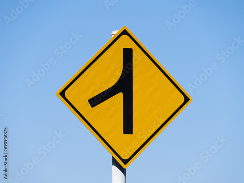道路標識(警戒標識)「合流交通あり」と青空。 