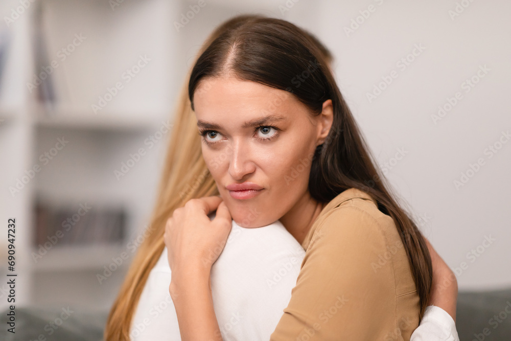 Dishonest young woman hugging her crying girlfriend at home Dishonest young woman hugging her crying girlfriend at home
