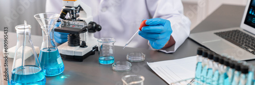 Scientist conduct chemical experiment in medical laboratory  carefully drop precise amount of liquid from pipette into test tube for vaccine drug or antibiotic development. Neoteric