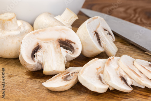Whole, halved and sliced button mushrooms on cutting board closeup