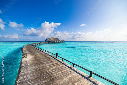 Best travel landscape. Exotic sunny island sea bay wooden pier and water villa over pristine lagoon leads into beautiful tropical paradise. Calm water  sunshine. Amazing vacation  luxury resort