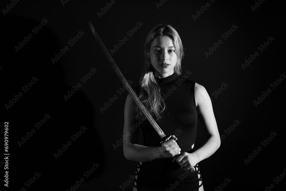 Low key portrait of young woman with katana sword in black and white Low key portrait of young woman with katana sword in black and white