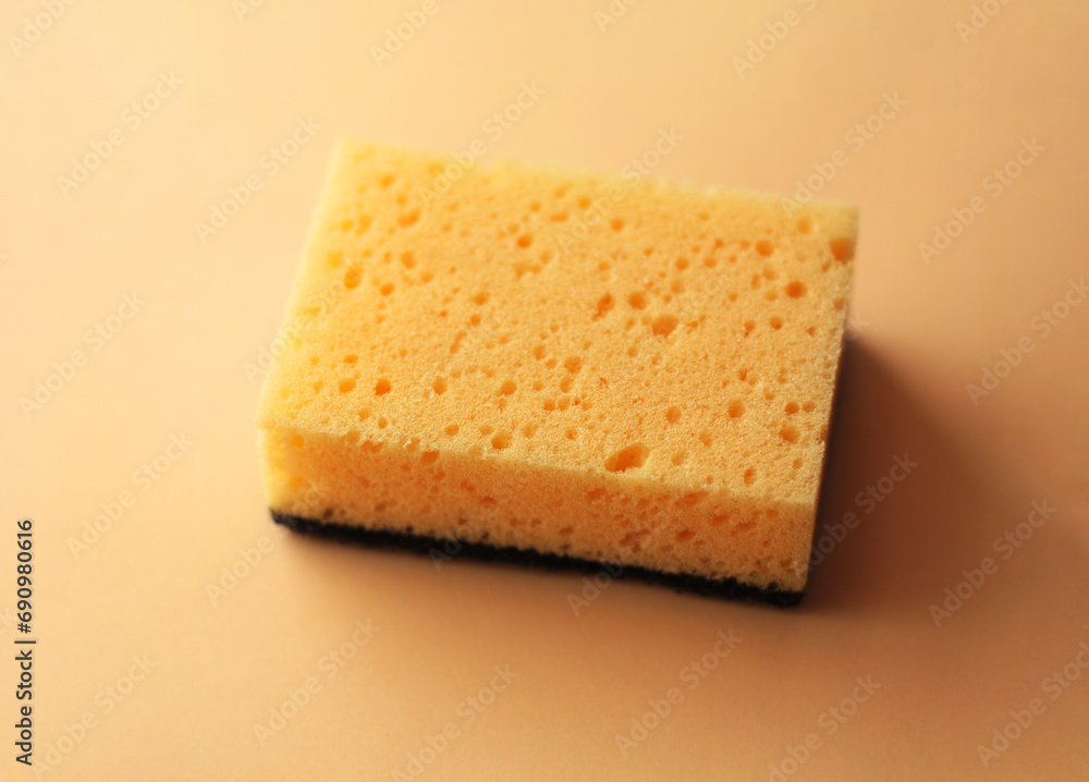 Cleaning sponge on a peach fuzz color background. Cleaning concept, cleaning service.Top view