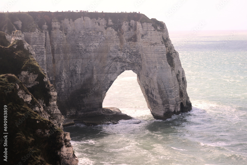 Sunny Etretat cliffs with backlight and tiny people on top, beautiful scenery and landscape at the ocean