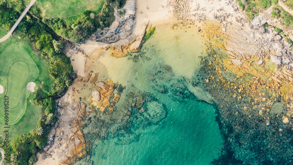 Naklejka premium Image taken with a drone at a zenith angle of a beach showing the green trees, the sand and the turquoise sea. Small and quiet beach in Sydney, Australia