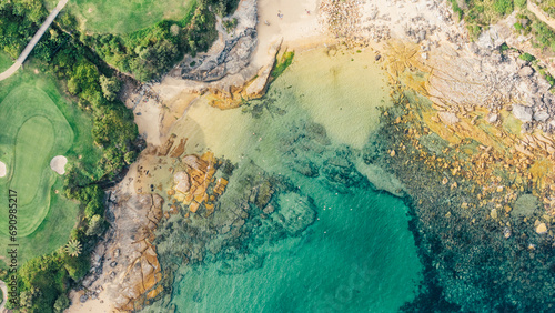 Image taken with a drone at a zenith angle of a beach showing the green trees, the sand and the turquoise sea. Small and quiet beach in Sydney, Australia