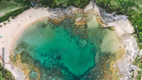 aerial aerial view from a drone towards the beach and the bay with turquoise water between the rocks and reefs of Little Bay beach in Sydney, Australia on a sunny and hot summer day.