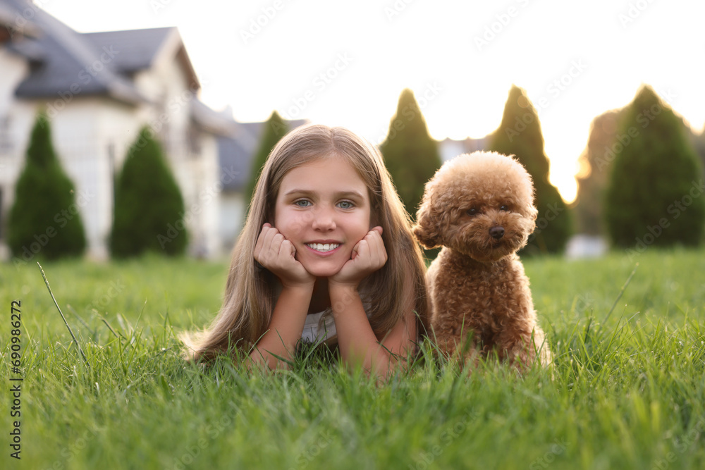 Beautiful girl with cute Maltipoo dog on green lawn in backyard Beautiful girl with cute Maltipoo dog on green lawn in backyard