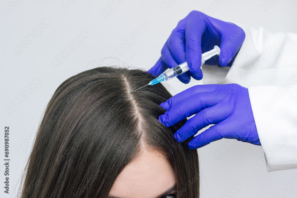 Fototapeta premium A young woman receiving injections into the scalp for hair growth. PRP therapy for hair Loss. Mesotherapy for hair growth. Hair Care