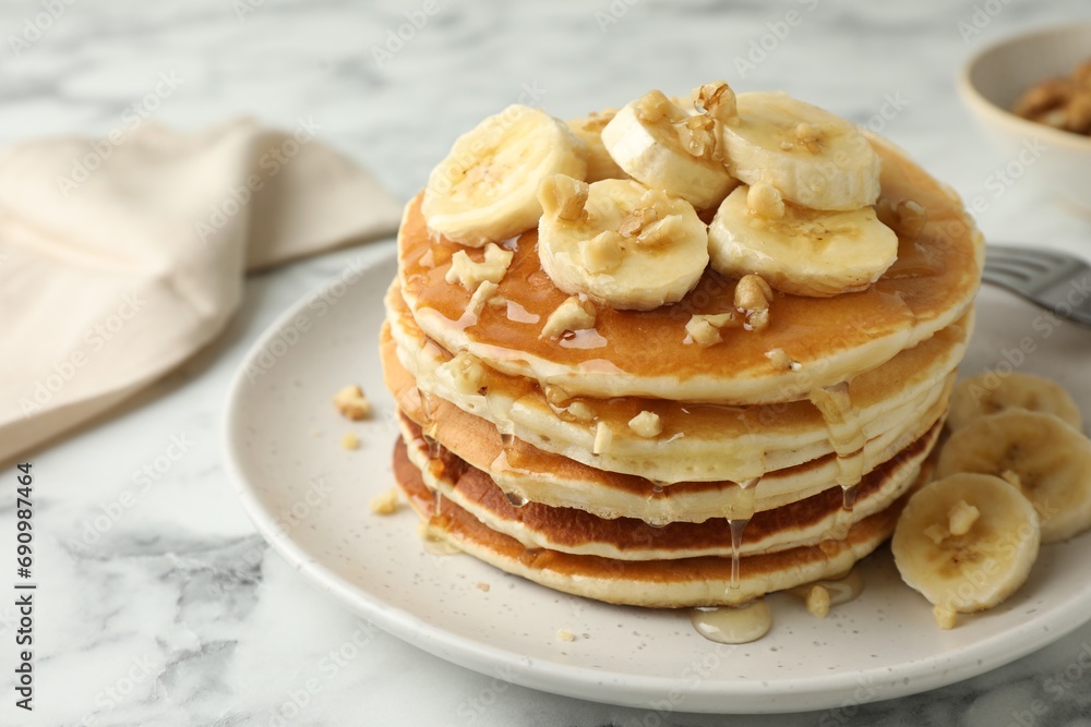 Delicious pancakes with bananas, walnuts and honey on white marble table, closeup Delicious pancakes with bananas, walnuts and honey on white marble table, closeup