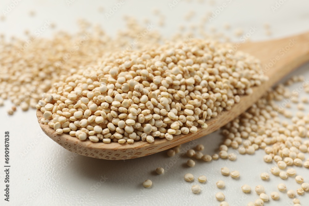 Spoon with dry quinoa seeds on white table, closeup Spoon with dry quinoa seeds on white table, closeup