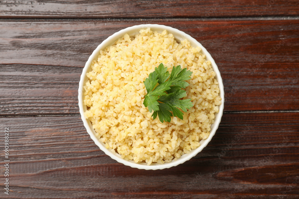 Delicious bulgur with parsley in bowl on wooden table, top view Delicious bulgur with parsley in bowl on wooden table, top view