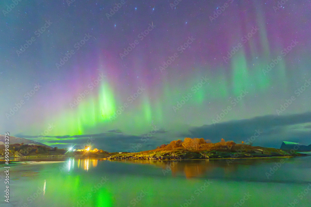 beautiful northern lights over lighthouse on the island of Hillesøy near Tromsø. dancing lady over house by the fjord, polar lights mirroring in the water of ocean in autumn, Aurora Borealis in Norway