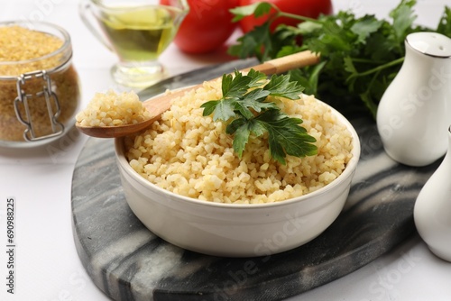 Delicious bulgur with parsley in bowl served on table, closeup