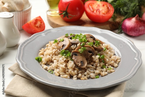 Delicious pearl barley with onion and mushrooms on white table, closeup