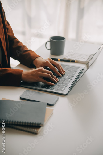 Attractive smiling young asian business woman work at home office, Asian woman working on laptop computer holding tablet.