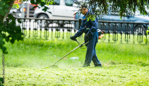 Backlit side view of a man removing grass with a trimmer