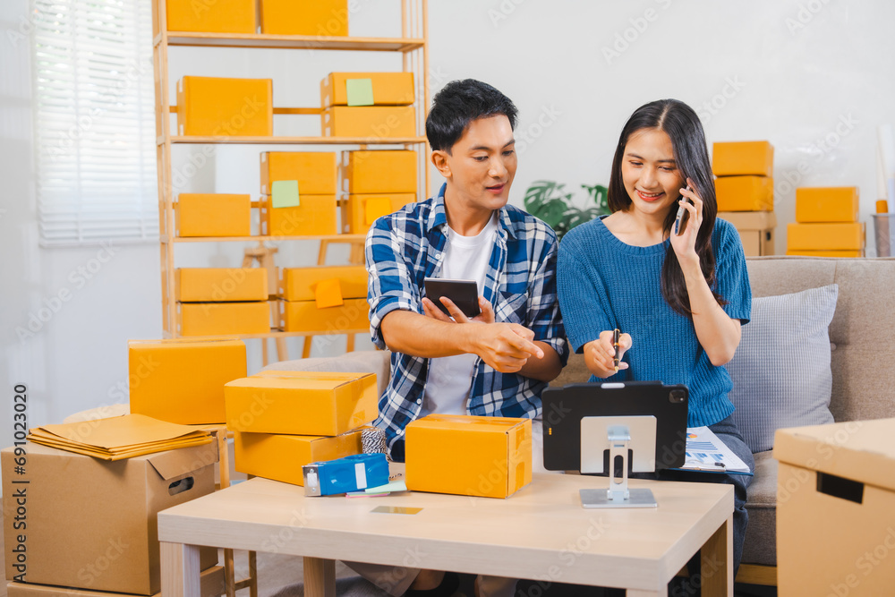 Asian people SME business woman and man couple joyfully showcasing products during a live stream in a room filled with packing boxes. Asian people SME business woman and man couple joyfully showcasing products during a live stream in a room filled with packing boxes.