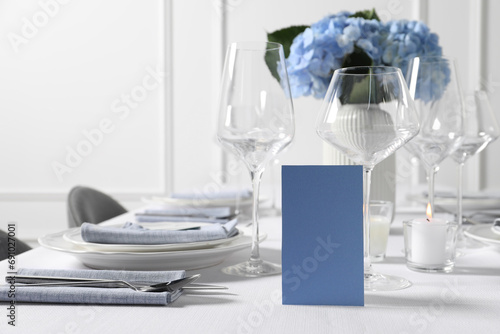 Beautiful table setting with blank card and floral decor indoors