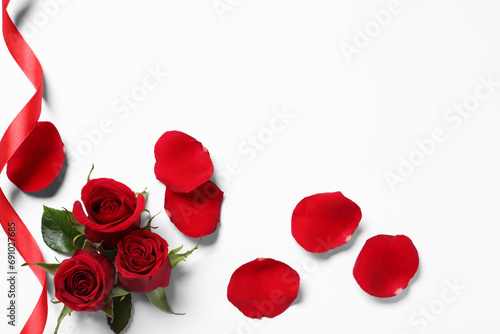 Beautiful red roses  petals and ribbon on white background  top view. Space for text