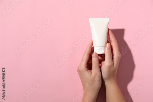 Woman with tube of hand cream on pink background, top view. Space for text © New Africa