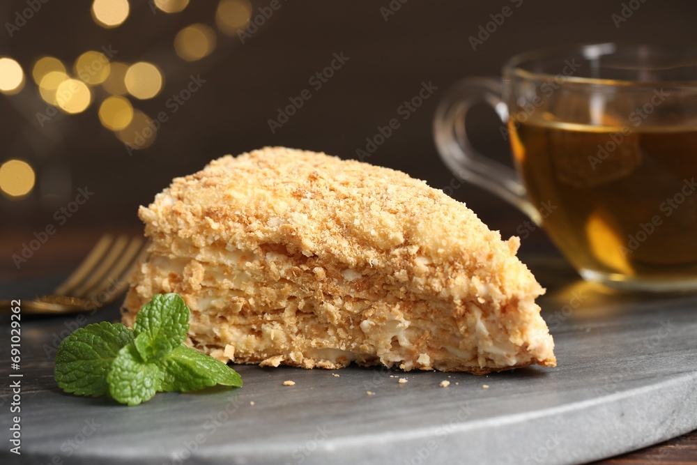 Piece of delicious Napoleon cake served on table, closeup
