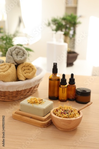Soap bar  dry flowers  bottles of essential oils  jar with cream and towels on wooden table indoors. Spa time
