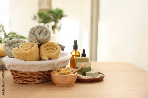 Dry flowers, soap bars, bottles of essential oils and towels on wooden table indoors, space for text. Spa time
