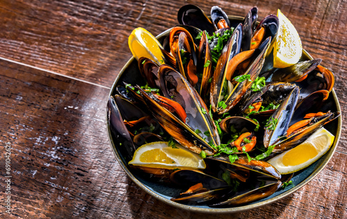 A plate of steamed mussels served with parsley and lemon