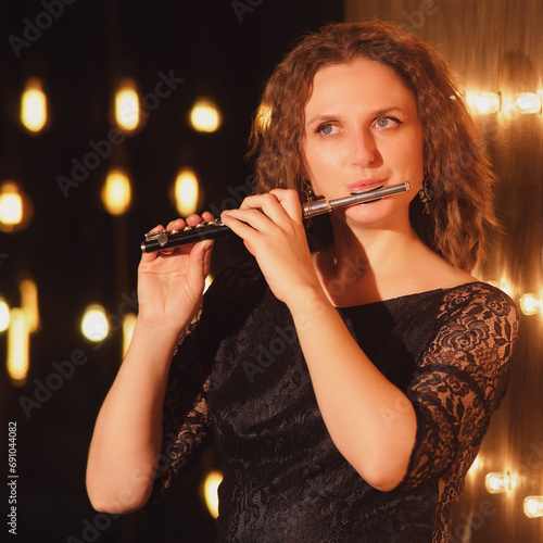 The female flautist, an accomplished musician, lit up the stage with her flute playing skills under the concert lights. photo