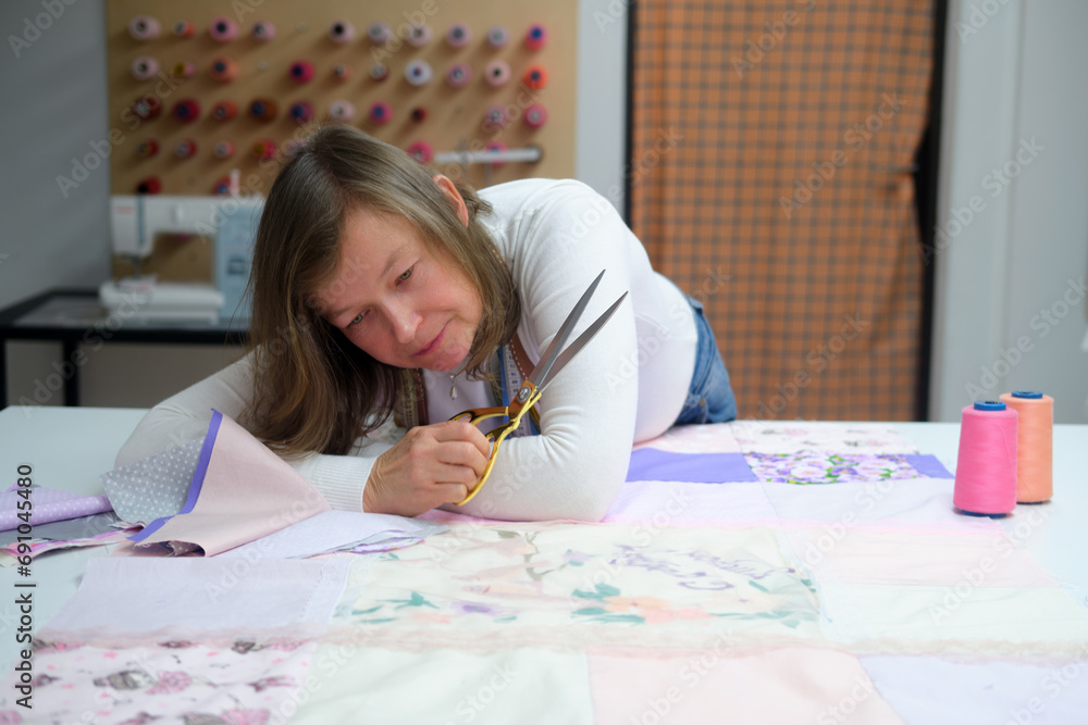 Adult fashion designer woman working on her designs in the sewing workshop. Selective focus. Adult fashion designer woman working on her designs in the sewing workshop. Selective focus.
