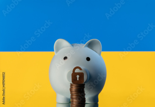 Symbolic lock and piggy bank against the background of the yellow-blue flag of Ukraine photo