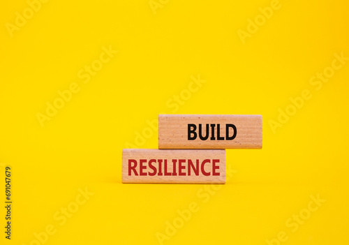 Build resilience symbol. Wooden blocks with words Build resilience. Beautiful yellow background. Business and Build resilience concept. Copy space.