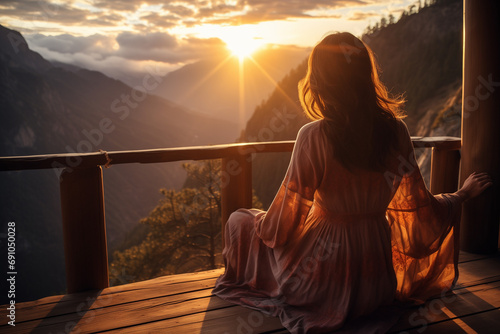 Picture from the back of a woman sitting on wooden porch looking into the mountains on hollidays photo