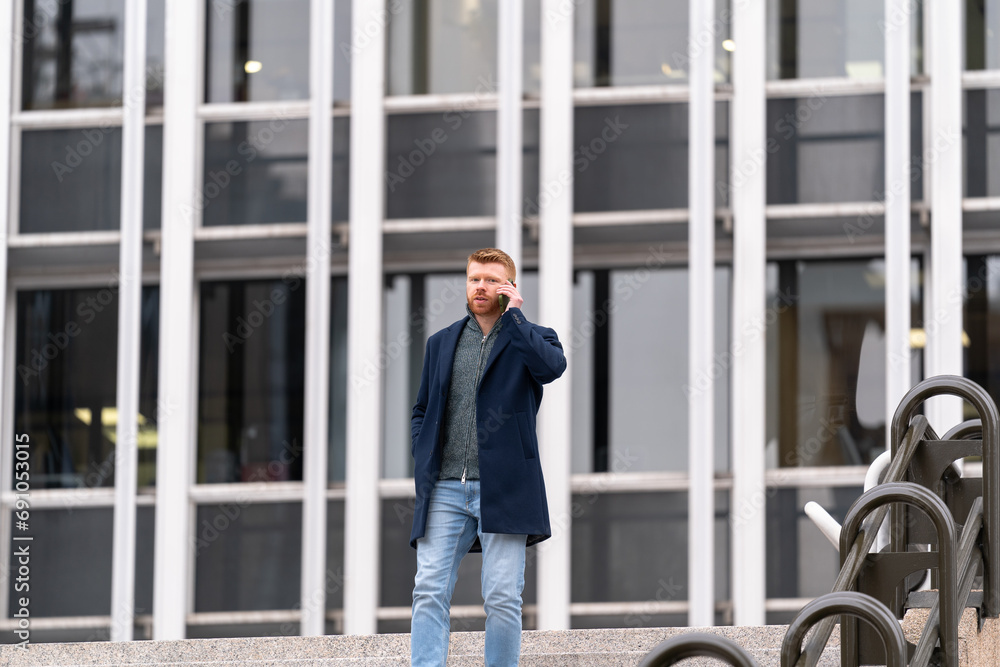 Red-haired businessman on a phone call, descending stairs with determination and professionalism in a business setting Red-haired businessman on a phone call, descending stairs with determination and professionalism in a business setting
