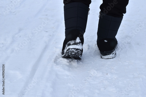 A woman walks through the snow. Feet in winter shoes.