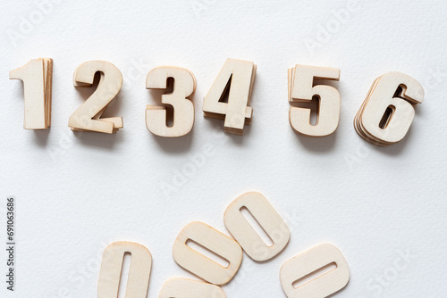 isolated piles of wooden numbers (1 to 6) and zeros on blank paper