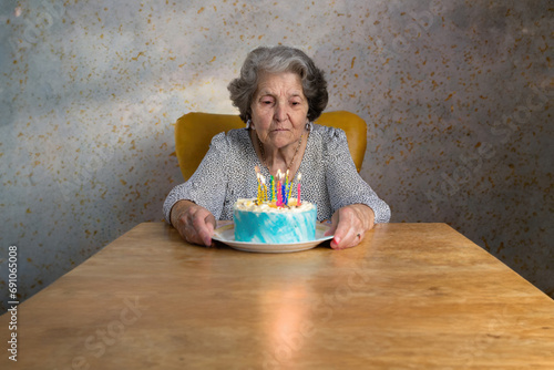 sad or depressed grandma, alone old woman on her birthday with cake photo