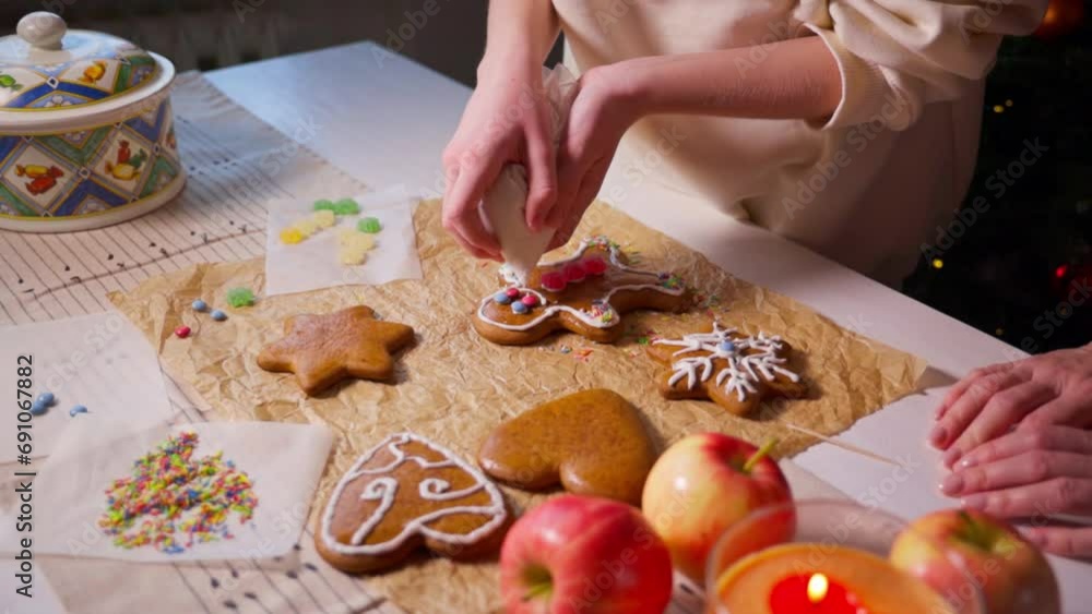 Happy girl coloring Christmas gingerbread cookies at home. Christmas decoration. Christmas tree with garlands. New Year and Christmas concept. Holiday atmosphere. High quality 4K footage Happy girl coloring Christmas gingerbread cookies at home. Christmas decoration. Christmas tree with garlands. New Year and Christmas concept. Holiday atmosphere. High quality 4K footage