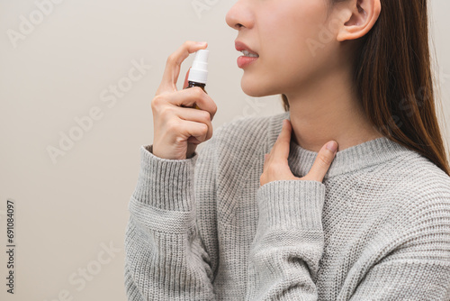 Health care treatment sore throat concept, sick pain asian young woman have cough symptom holding medicine bottle, using spray in mouth to protect disease from bacteria, illness from virus infection. photo