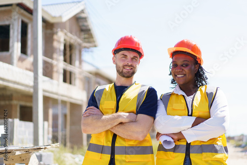 Portrait of construction contractors smile and look at camera at the construction site. Male and female foreman or civil engineers portrait.