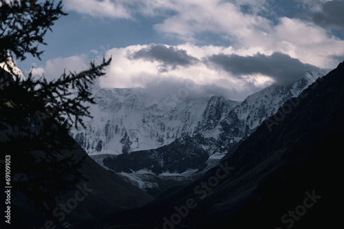 Landscape of high snowy mountains covered with clouds during sunset, Altai mountains