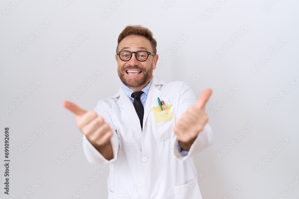 Middle age doctor man with beard wearing white coat approving doing positive gesture with hand, thumbs up smiling and happy for success. winner gesture. Middle age doctor man with beard wearing white coat approving doing positive gesture with hand, thumbs up smiling and happy for success. winner gesture.