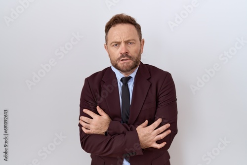 Middle age business man with beard wearing suit and tie shaking and freezing for winter cold with sad and shock expression on face