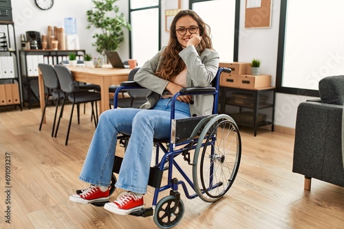 Young beautiful hispanic woman business worker smiling confident sitting on wheelchair at office