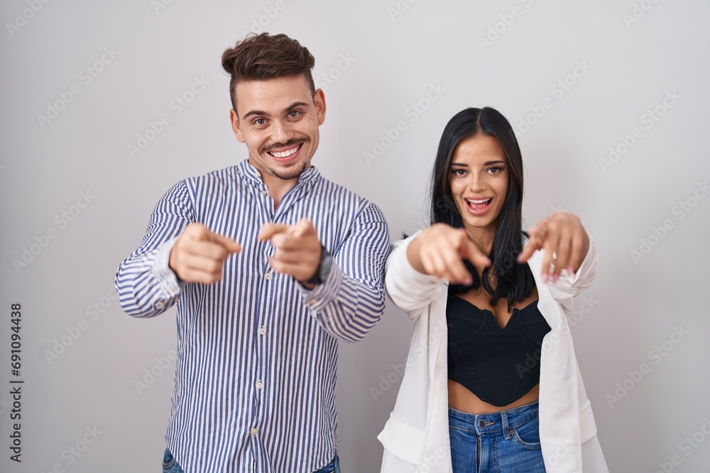 Young hispanic couple standing over white background pointing to you and the camera with fingers, smiling positive and cheerful Young hispanic couple standing over white background pointing to you and the camera with fingers, smiling positive and cheerful